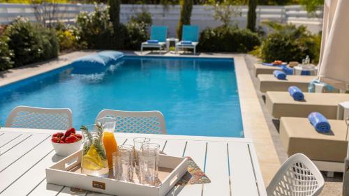 a tray of drinks on a table next to a swimming pool at Diamond villas in Protaras