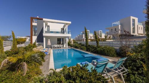 a villa with a swimming pool and two chairs at Diamond villas in Protaras