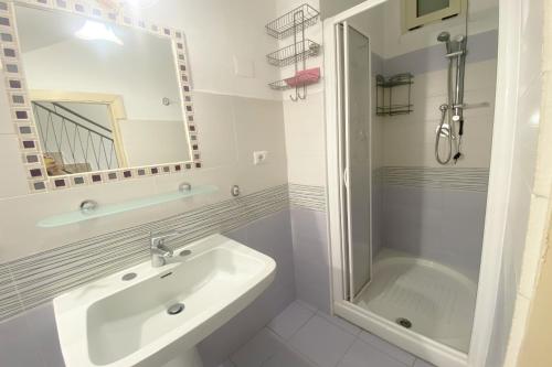 a white bathroom with a sink and a shower at La casa di Mariedda in Dorgali