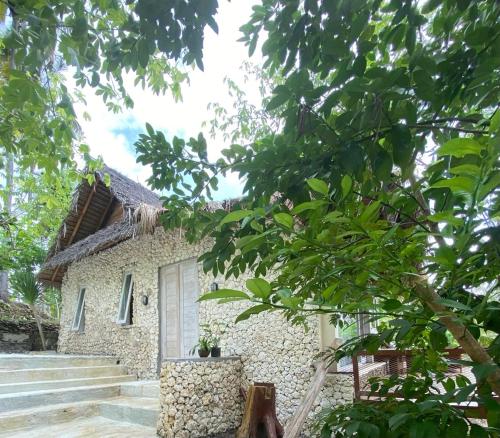 a stone house with a white door and some trees at Gading Tree House in Nusa Penida