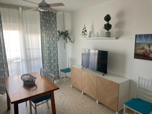 een woonkamer met een flatscreen-tv en een tafel bij Azvalia - Valparaíso beach apartment - Piscina y parking gratis in El Puerto de Santa María