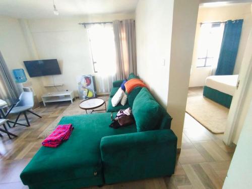 a living room with a green couch and a bed at pgs plaz in Nakuru