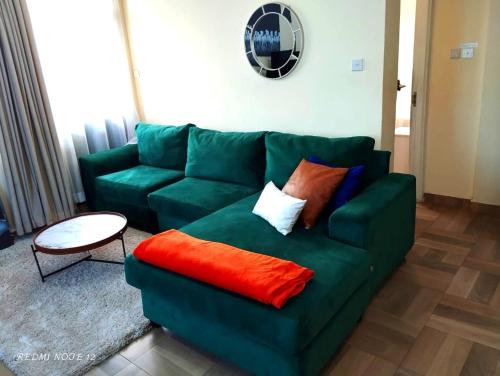 un sofá verde con almohadas en la sala de estar en pgs plaz en Nakuru