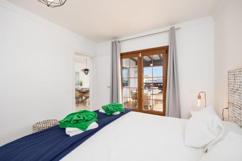 a bedroom with a white bed with green towels on it at Villa Saona in Playa Blanca