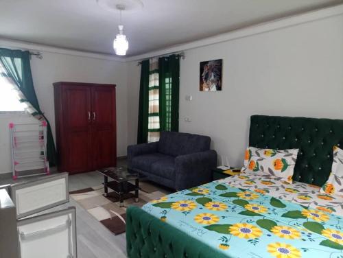a bedroom with a bed and a couch and a chair at Makeena Berry Cosy Mboa - OLYMPE in Douala