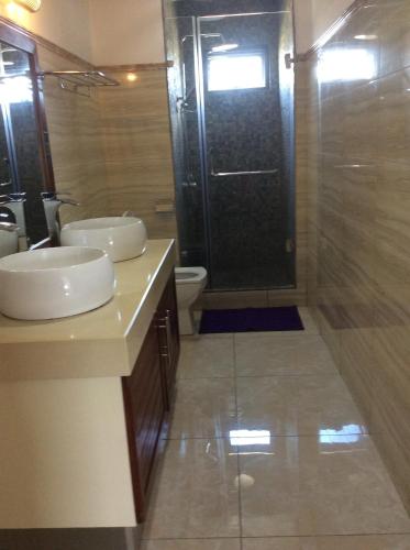 a bathroom with a shower and two sinks and a toilet at Fortuna Beach in Flic-en-Flac