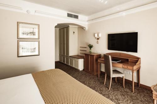 a hotel room with a desk and a television at Corinthia Palace Malta in Attard