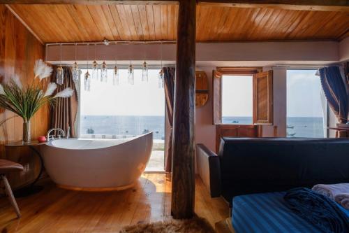 ein Bad mit einer Badewanne, einem Sofa und einem Fenster in der Unterkunft Oceanside Villa Phuquy Island in Cu Lao Thu