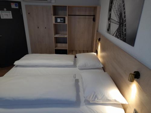 three beds in a room with white sheets at Hotel am Park in Rust