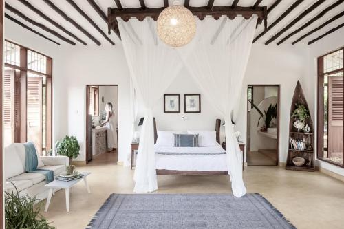 a bedroom with a bed with a white canopy at Tarangau Retreat in Kilifi
