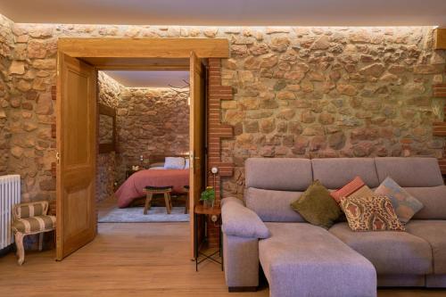 a living room with a couch and a stone wall at Masia de Can Ferrer in Arbúcies