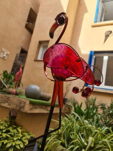 a red glass bird sculpture in front of a building at Hôtel de la Mer in Valras-Plage