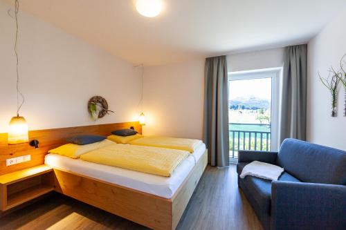 a bedroom with a bed and a couch and a window at Seehaus Winkler in Weissensee