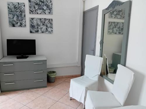 a living room with two white chairs and a television at La Mandragola Garden in Berra