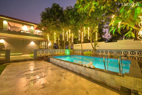 a swimming pool in the middle of a yard at night at EKO STAY- Brickstone Villa in Igatpuri