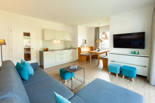 a living room with a blue couch and a kitchen at Seehaus Winkler in Weissensee