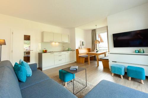 a living room with a blue couch and a kitchen at Seehaus Winkler in Weissensee