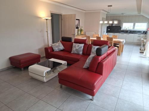 sala de estar con sofá rojo y mesa en Am Hochkreuz, en Amblève