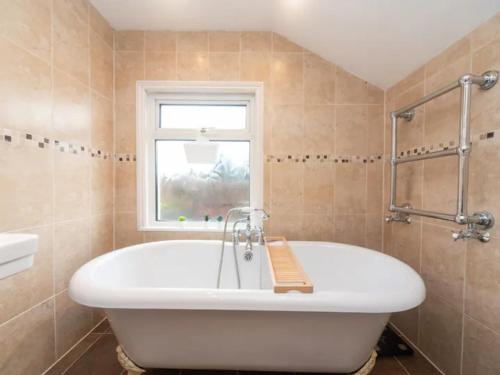 a white tub in a bathroom with a window at Pass the Keys Modernised family-friendly cottage in Surbiton