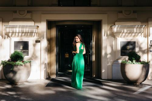 una mujer con un vestido verde parada fuera de un edificio en The Ritz-Carlton, Vienna en Viena