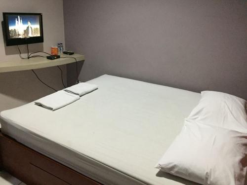ein Bett mit weißer Bettwäsche und ein TV auf einem Schreibtisch in der Unterkunft Griya Mitra Kost in Jakarta