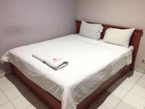 ein Bett mit weißer Bettwäsche und einem weißen Handtuch darauf in der Unterkunft Griya Mitra Kost in Jakarta