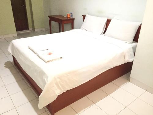 ein Bett mit weißer Bettwäsche und Kissen darauf in der Unterkunft Griya Mitra Kost in Jakarta