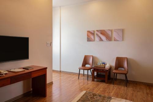 a living room with two chairs and a flat screen tv at Mekong Gia Lai Hotel - Me Kong Pleiku in Pleiku