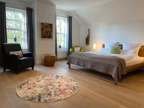 Hotel Altes Dichterhaus في Timmel: غرفة نوم بسرير وكرسي وسجادة