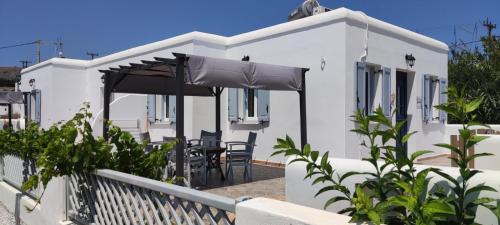 ein weißes Haus mit einer Terrasse mit Stühlen und einem Sonnenschirm in der Unterkunft Chrysiis House 1 in Maltezana