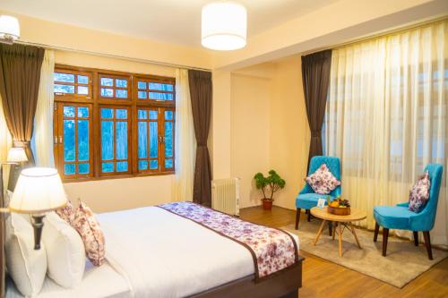 een slaapkamer met een bed en 2 stoelen en een raam bij Voyage Dreamvilla Retreat in Pelling