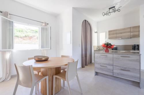 - une cuisine avec une table en bois et des chaises blanches dans l'établissement Le Trois MC - Appt climatisé proche de la mer, à LʼÎle-Rousse