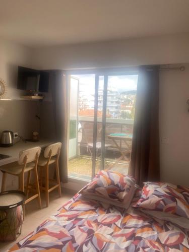 - une chambre avec un lit, une table et un balcon dans l'établissement studio neuf à cannes, à Cannes