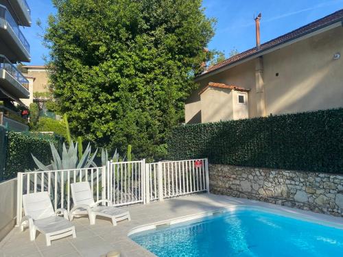 une piscine avec deux chaises et une clôture dans l'établissement studio neuf à cannes, à Cannes