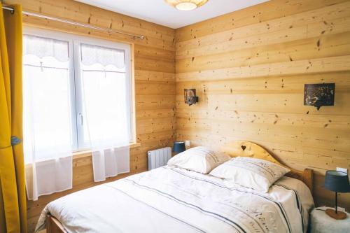 Ban-sur-Meurthe-ClefcyにあるChalet : Secteur Gérardmer.の木製の壁のベッドルーム1室、ベッド1台(枕付)
