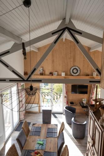 - un salon avec une table, des chaises et une horloge dans l'établissement Chalet : Secteur Gérardmer., à Ban-sur-Meurthe-Clefcy