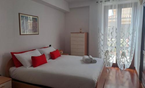 a bedroom with a bed with red pillows and a window at Nel cuore di Oristano in Oristano