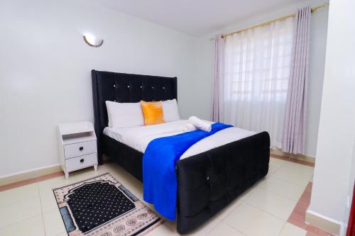 1 dormitorio con 1 cama grande y cabecero negro en Garden City furnished apartment, en Nairobi