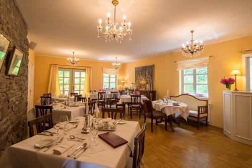 a dining room with tables and chairs and chandeliers at Romantik Hotel Landhaus Bärenmühle in Frankenau