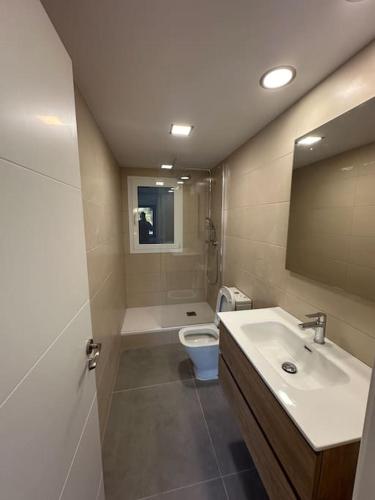 uma casa de banho com um lavatório, um WC e um espelho. em Apartamento a 1 minuto de la playa em Castelldefels