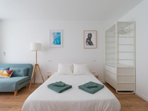 1 dormitorio con 1 cama blanca y 1 sofá azul en HomeForGuest Estudio Brisa Canteras con terraza, en Las Palmas de Gran Canaria