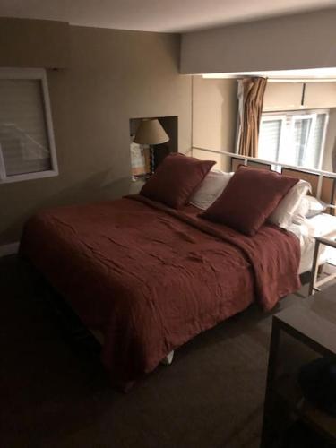 una camera da letto con un grande letto con lenzuola e cuscini rossi di Charming flat near Bois de Boulogne Paris a Neuilly-sur-Seine