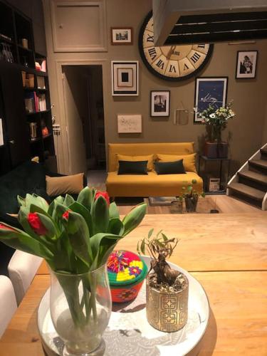 a living room with a table with a vase with flowers at Charming flat near Bois de Boulogne Paris in Neuilly-sur-Seine