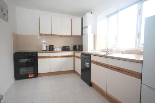 a kitchen with white cabinets and a black dishwasher at 28A Benedict Street in Glastonbury