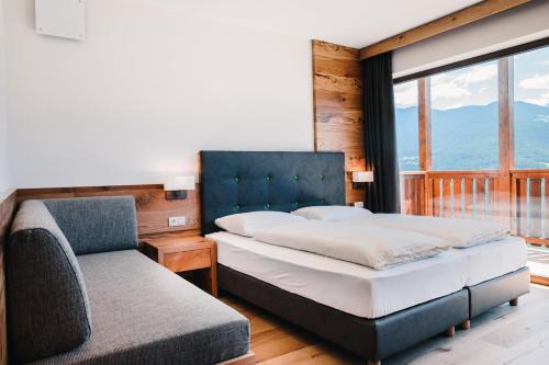 ein Schlafzimmer mit einem Bett, einem Sofa und einem Fenster in der Unterkunft Gasthof Hotel Wöhrmaurer in Feldthurns