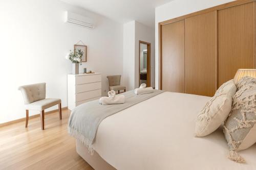 a bedroom with a large white bed and a chair at Golden Terrace Delight in São Martinho do Porto