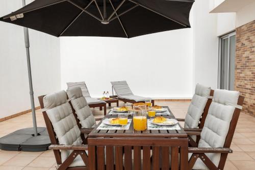 a dining table with an umbrella and some orange juice at Golden Terrace Delight in São Martinho do Porto