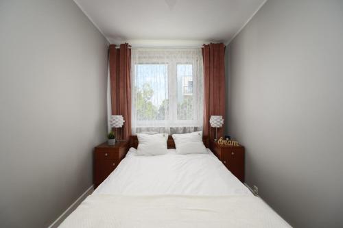 a bedroom with a white bed and a window at PCK 1 ProstyWynajem Gdańsk Brzeźno in Gdańsk