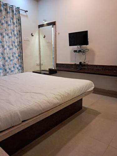 a bedroom with a bed and a flat screen tv at Tulsi Villa Bunglow in Mahabaleshwar