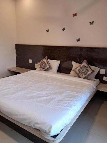 a large bed with white sheets and pillows on it at Tulsi Villa Bunglow in Mahabaleshwar